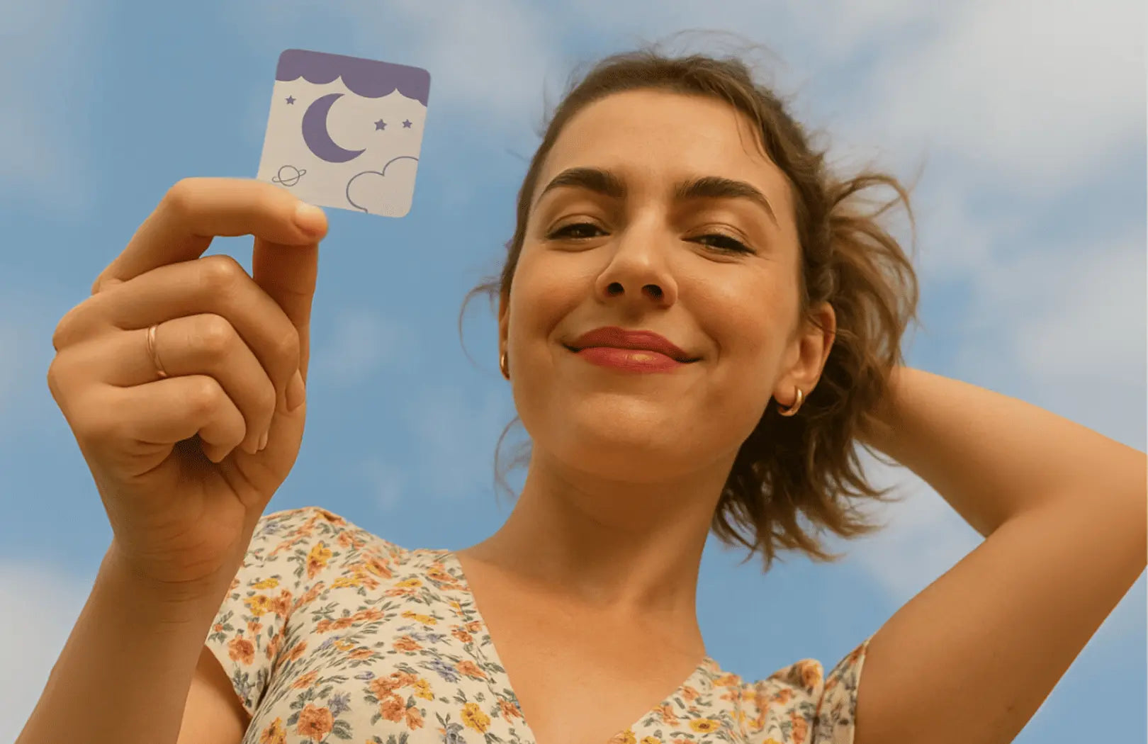 Smiling woman holding a Vitalisys Sleep Patch against the sky, symbolising the future of natural and wearable sleep aids.
