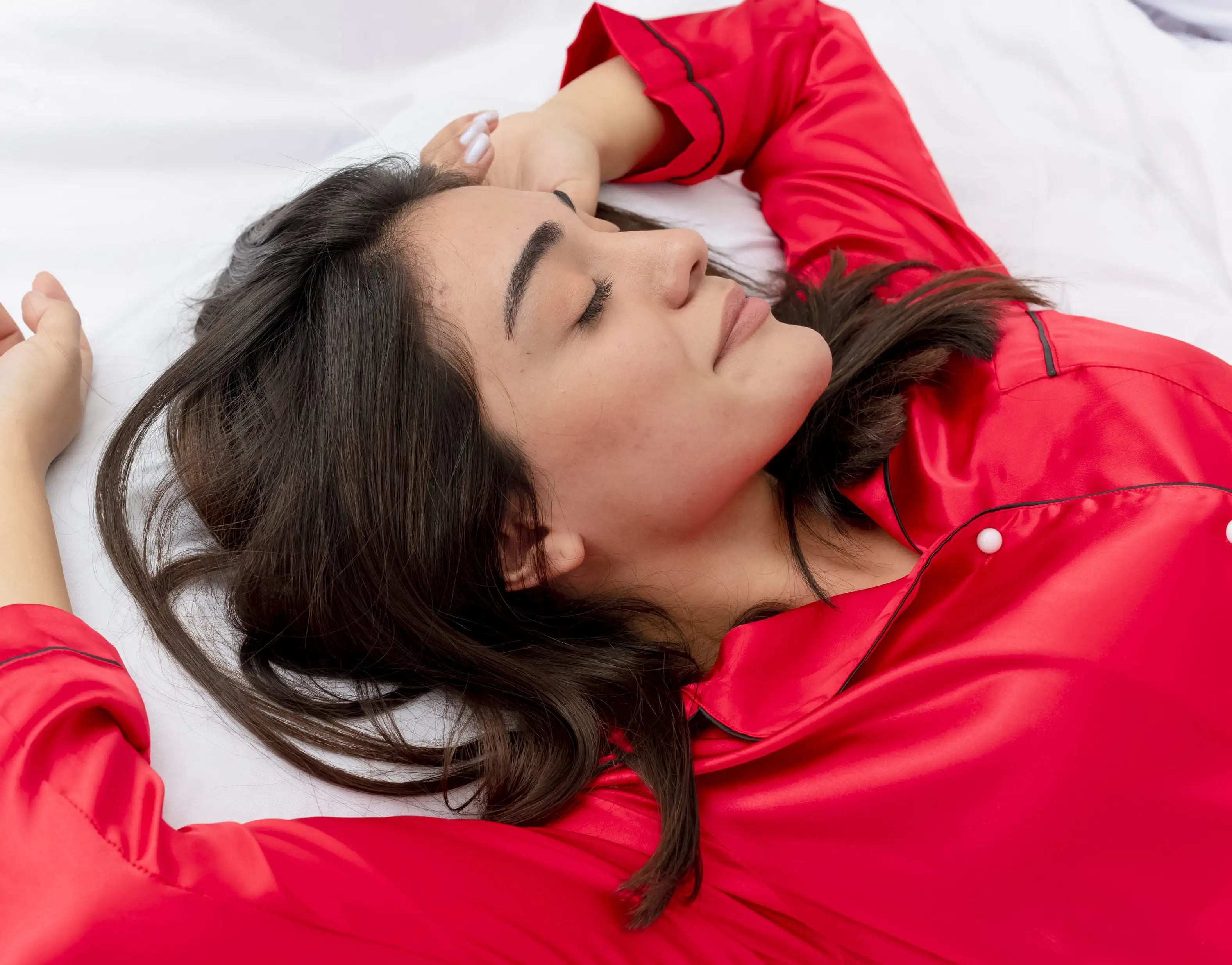 Woman sleeping peacefully in red pyjamas, representing emotional balance and the connection between sleep and mental health.
