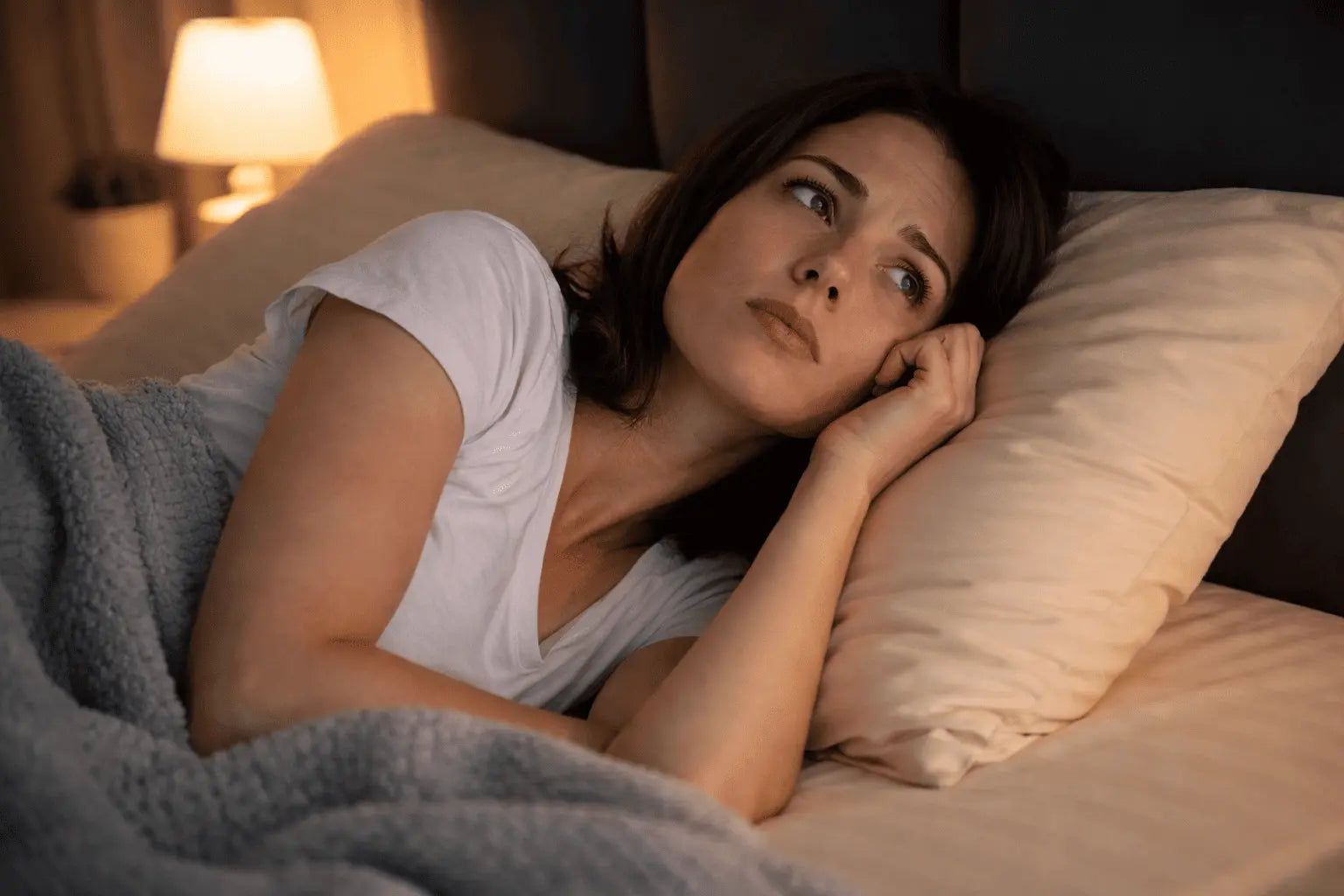 Woman lying awake in bed at night, feeling anxious and unable to fall asleep