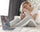 Woman sitting on her bed feeling drained and low on energy while holding her glasses.