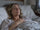 Woman in her 50s lying in bed in the morning with a hand on her chest, looking anxious as soon as she wakes up