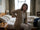 Woman in her 50s sitting on the edge of the bed in the morning holding her lower back in pain after a poor night's sleep