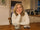 Woman in her 50s sitting at a kitchen table in the evening with a cup of tea and a piece of chocolate, looking thoughtful