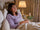 Woman in her 50s propped up in bed with pillows resting while ill, warm tea and tissues on the bedside table"