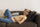 Woman lying on a sofa with a hand on her forehead, feeling low energy and struggling to recover on a rest day.