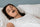 Woman sleeping in bed with her mouth slightly open, illustrating shallow breathing and the effects of poor sleep quality, concept for natural sleep improvement by Vitalisys.