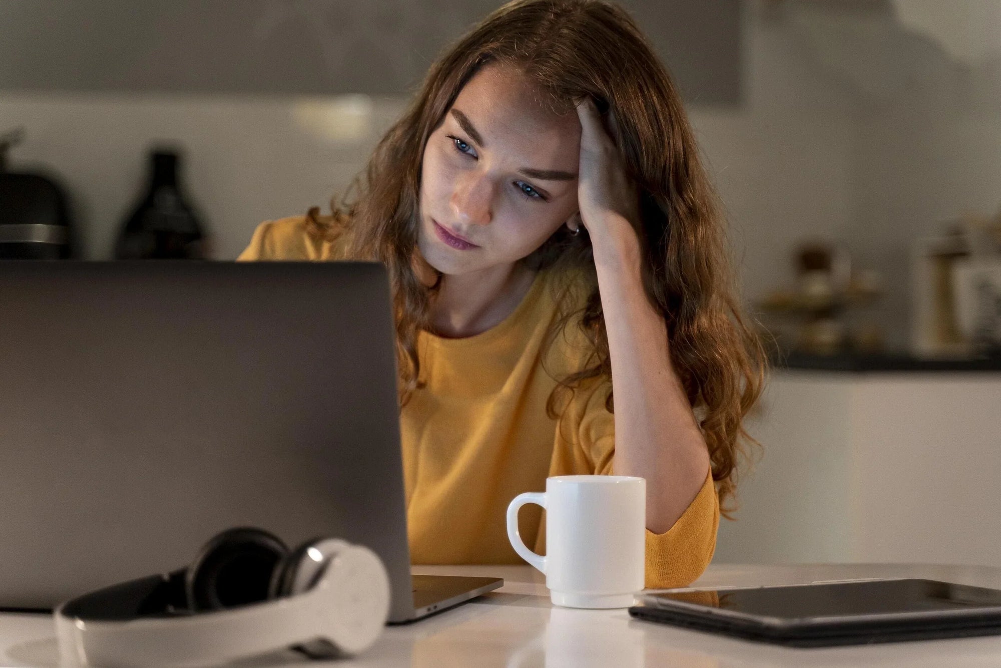 Tired woman working on her laptop in the afternoon, showing signs of an energy crash and low motivation.